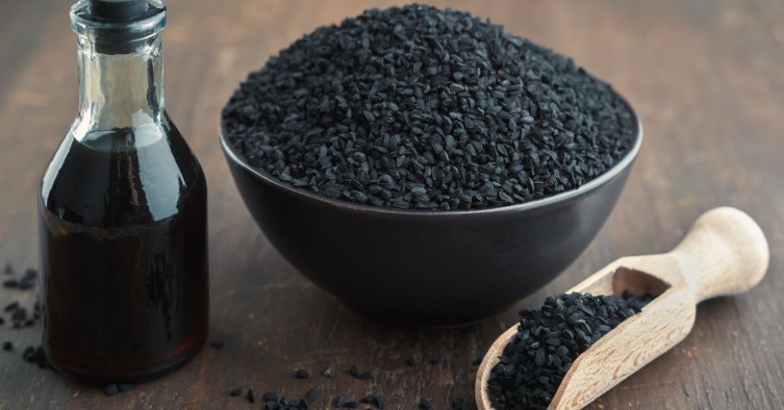 ciotola di semi di cumino nero e bottiglia di olio di cumino nero