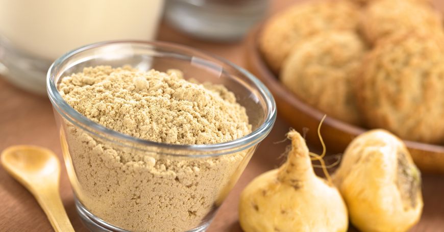 bowl of maca powder and two whole maca roots