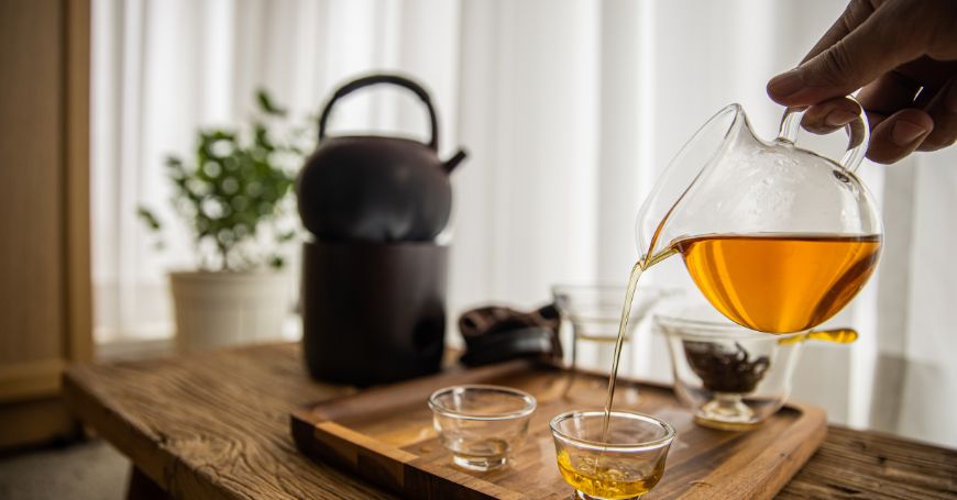 persona vertiendo una tetera de té amarillo en una taza