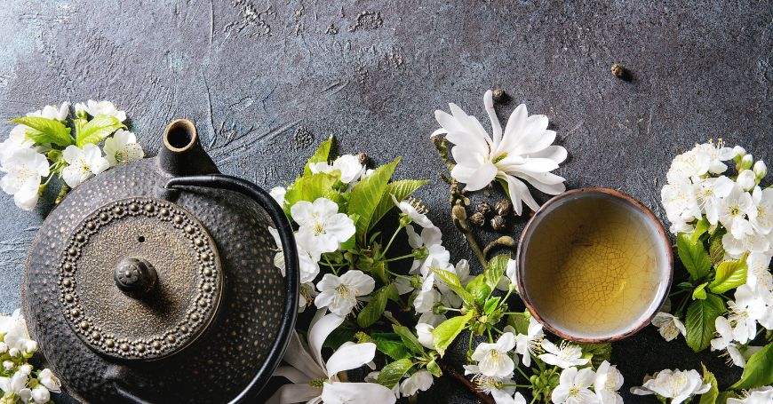 théière et tasse de tisane pour la grossesse entourées de fleurs