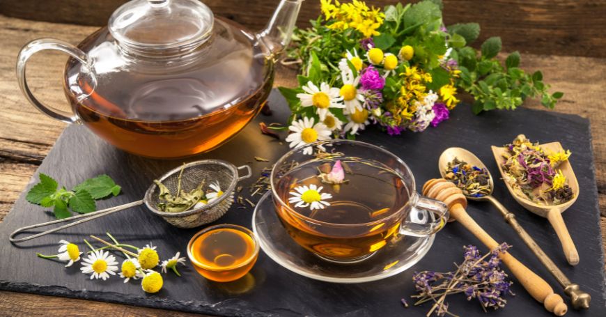 tazza di tisana primaverile con teiera e fiori e foglie